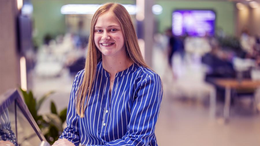 Chloe Miller stands in the Foster Center on Baylor campus, smiling at the camera